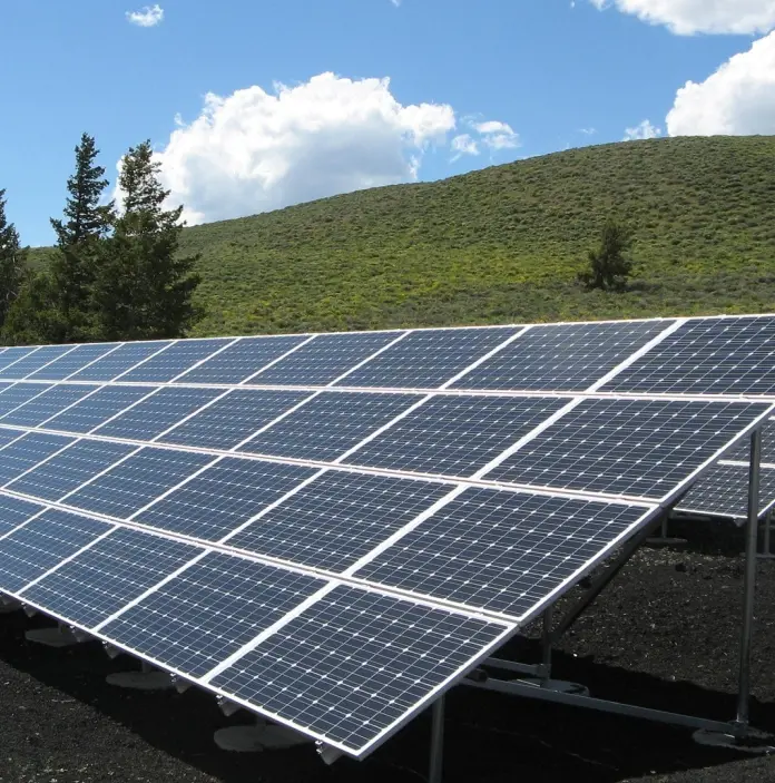 Solar panels in front of green hills.