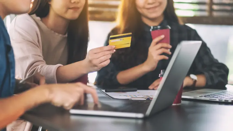 Person holding card up in front of laptop