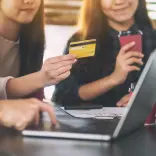 Person holding card up in front of laptop